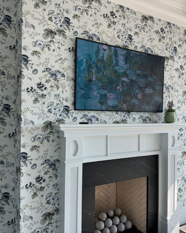 Living room wrapped in blue and gray floral wallpaper around a white painted fireplace mantel