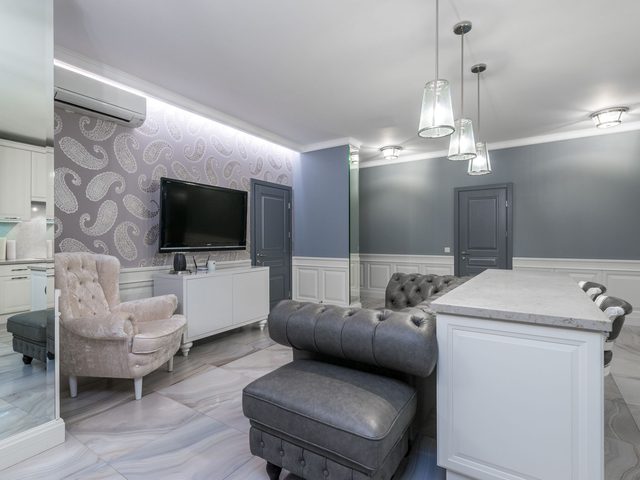 Transitional living space with a lilac paisley accent wall above white wainscoting and gray tufted seating